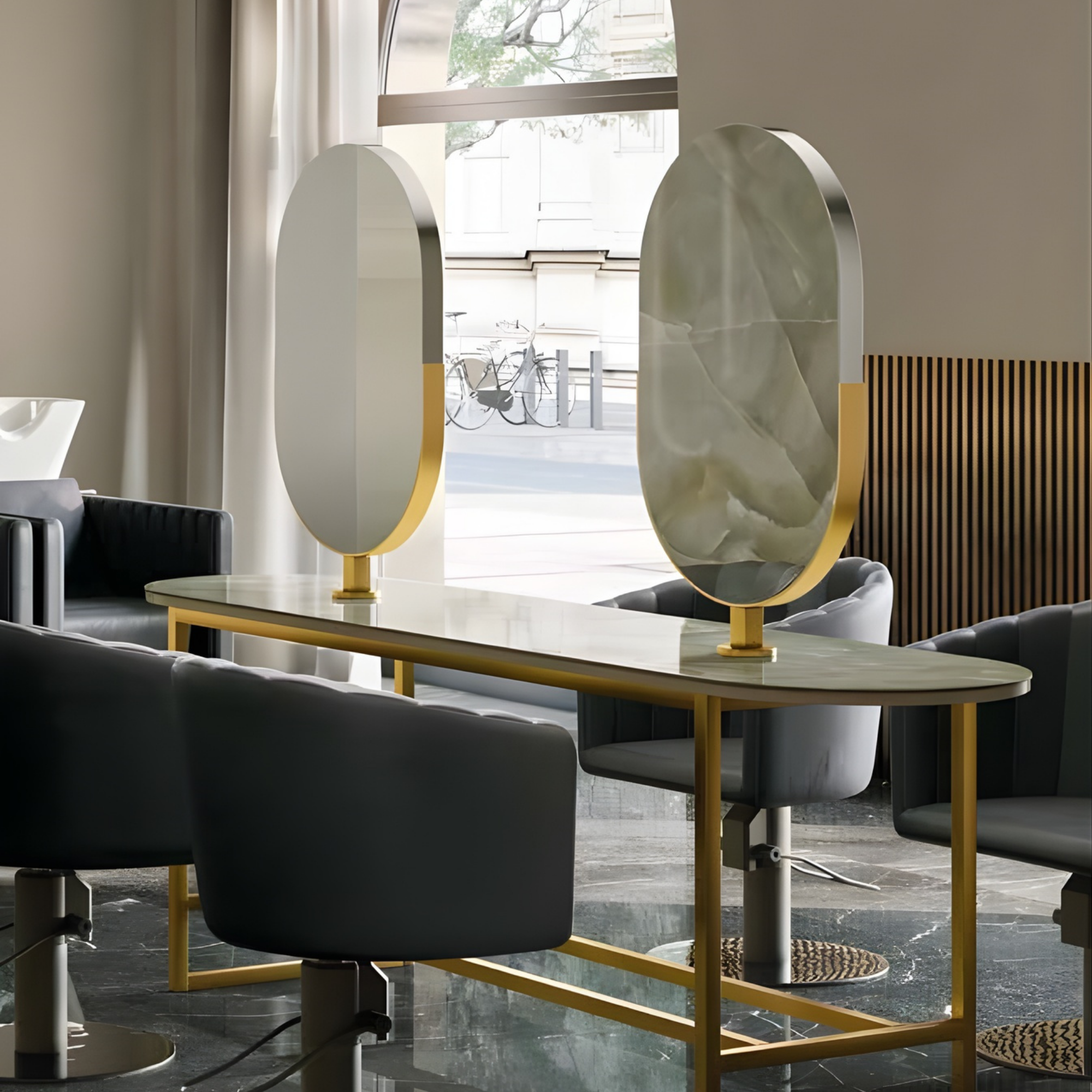moderan frizerski prostor s tamnosivim frizerskim stolicama i ovalnim ogledalima s mramornim uzorkom i zlatnim okvirima