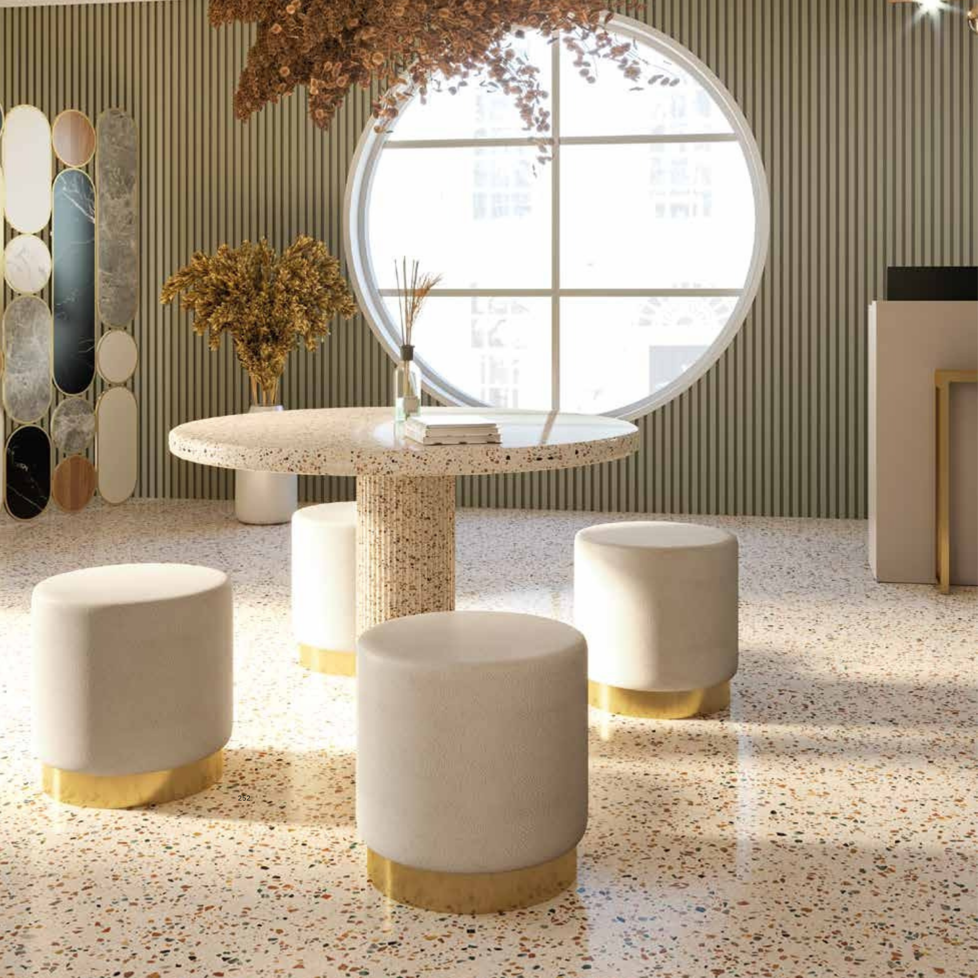 elegantan salon s okruglim prozorom, terrazzo stolom i sjedalima s bijelim presvlakama i zlatnim bazama, uređen u toplim tonovima s dekorativnim suhim biljkama